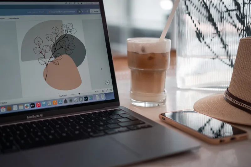 Close-up of a laptop displaying Photoshop on a desk with digital design equipment