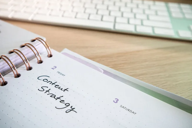 Clean workspace with a notebook and laptop representing consistent email newsletter planning and scheduling