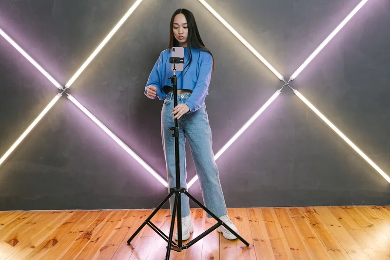 Person holding a smartphone on a tripod, preparing to record a TikTok video