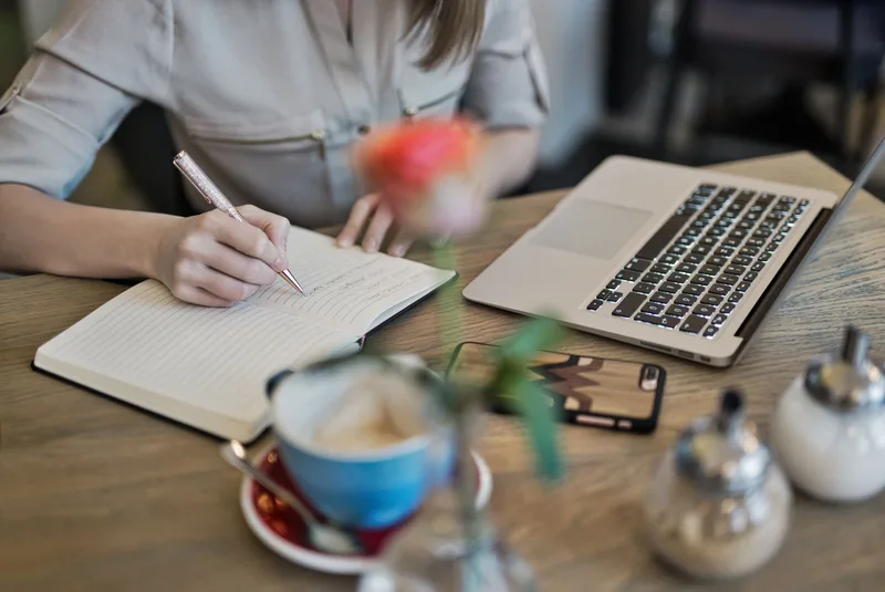 Creator sitting at a desk writing thread ideas in a notebook, planning Twitter content structure