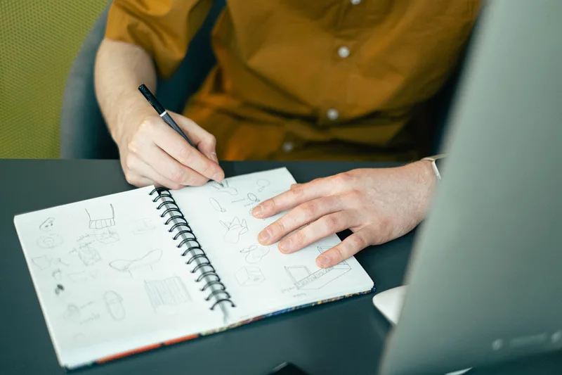 Creator writing ideas and planning content structure in a notebook at a desk