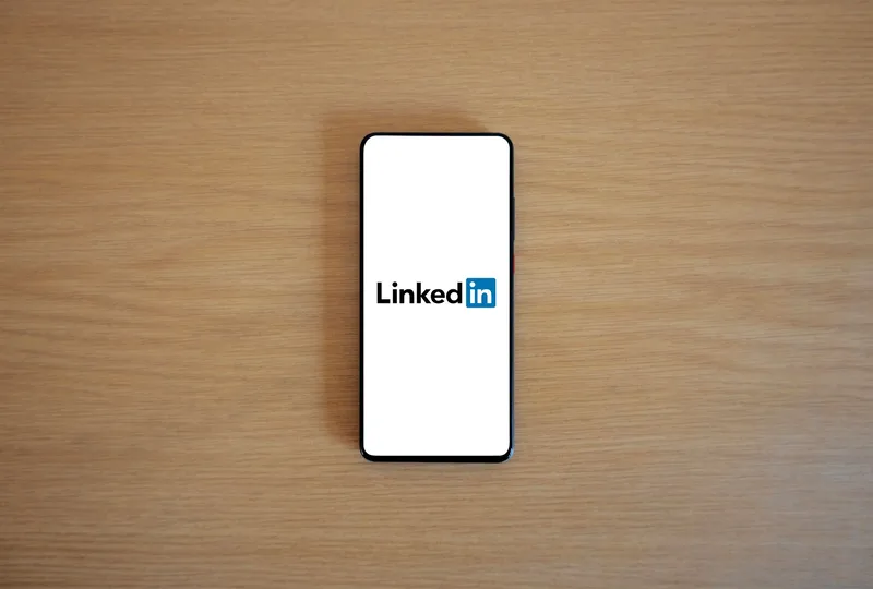 Notebook with handwritten notes and a laptop open beside it, representing LinkedIn content planning and format selection