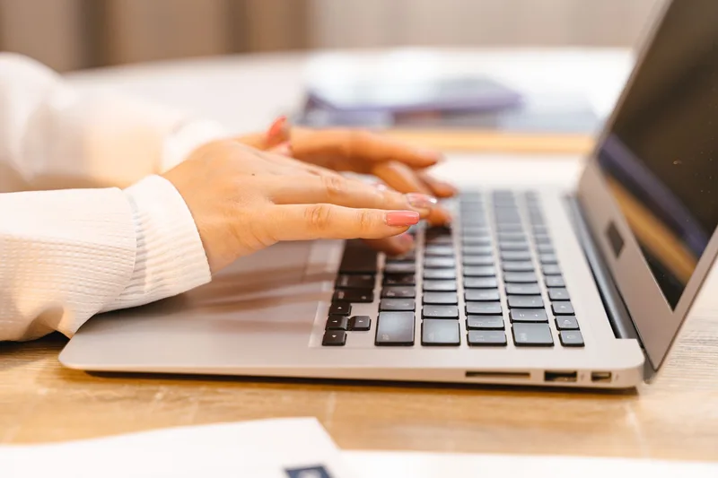 Hands on a laptop, representing focused professional content creation for LinkedIn