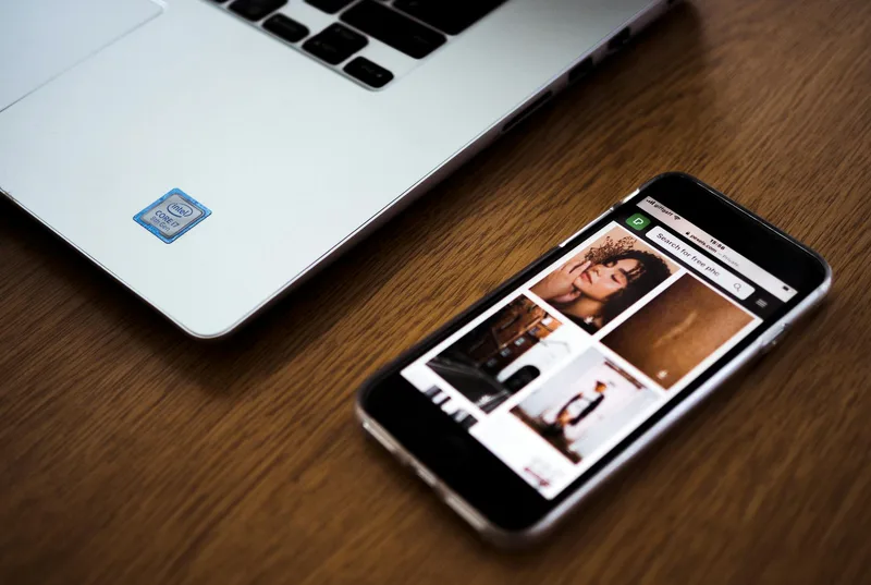 Smartphone next to a laptop on desk, representing LinkedIn&rsquo;s mobile and desktop newsletter experience