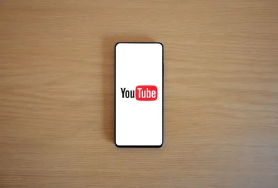 Woman holding a smartphone displaying various apps representing mobile YouTube browsing experience