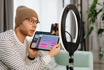 Man using a tablet to design creative content at his desk representing the thumbnail design process